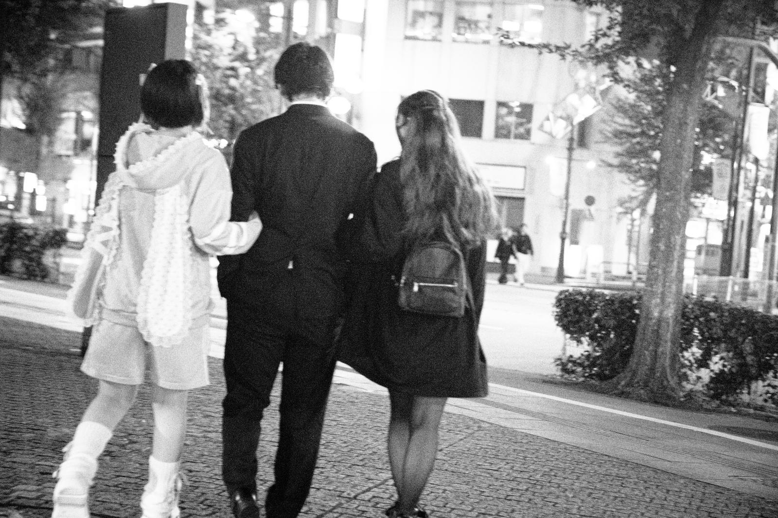夜の街を歩く女性の後ろ姿